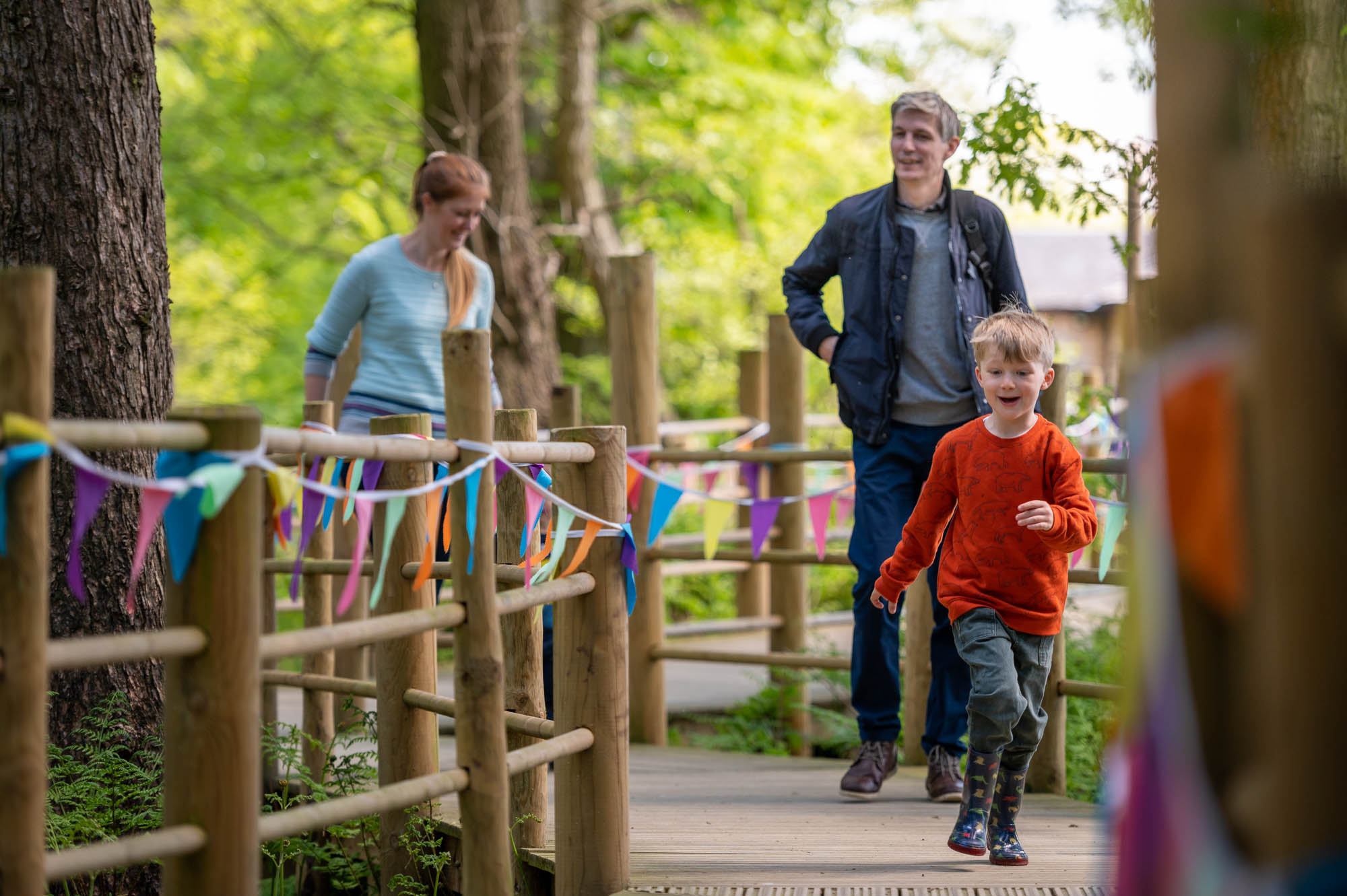 Family running down wooden trail at bewilderwood