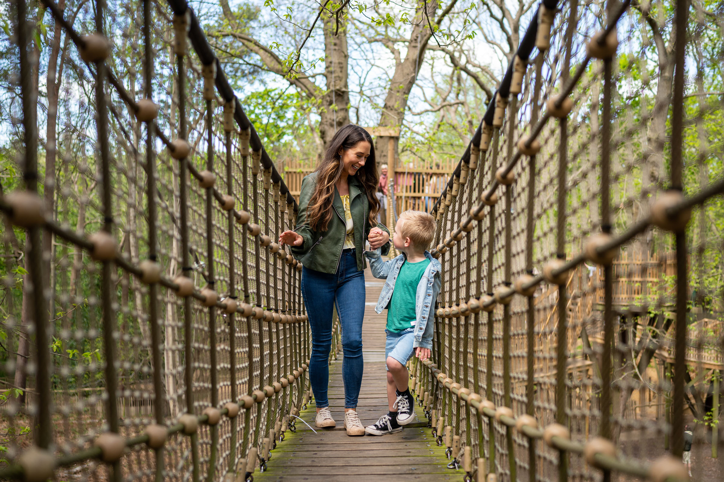 Mum and son holding hands on a bridge at Bewilderwood