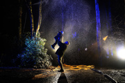 Man lifting a child into the air in a woodland at night, with snow falling