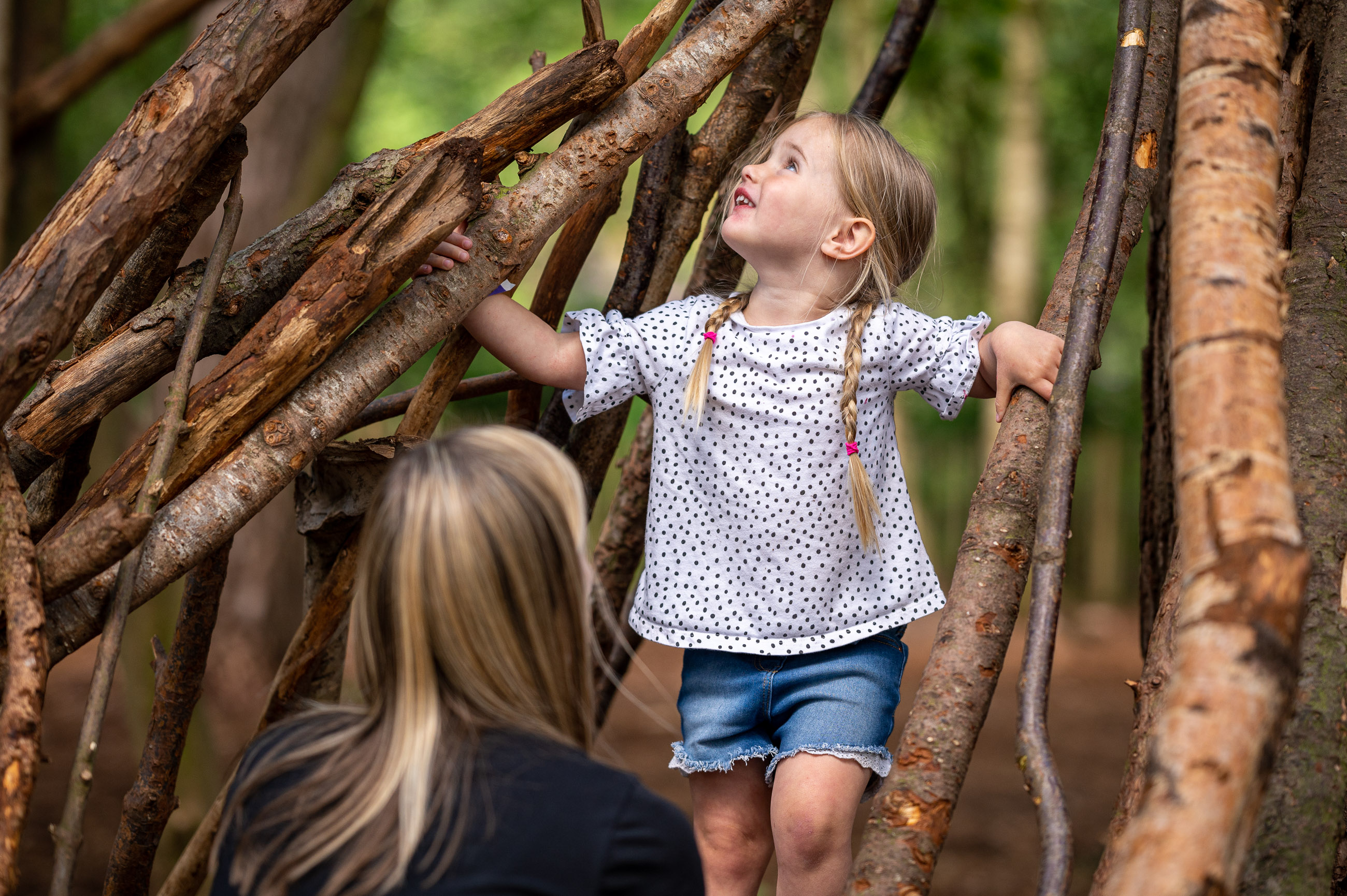 Mum and daughter building a den out of sticks at bewilderwood