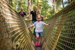 A Family walking across a narrow bridge.