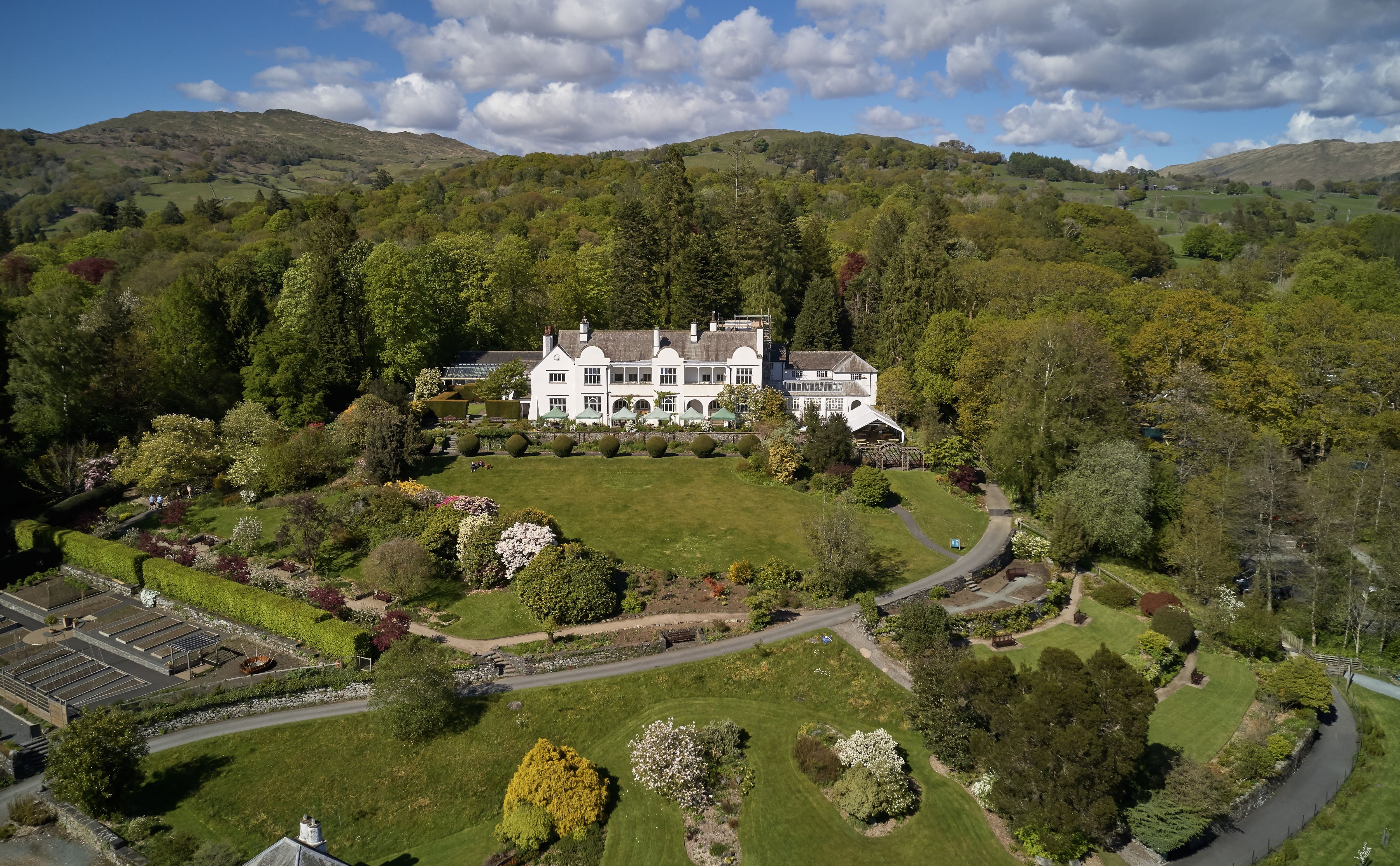 Aerial shot of a large white building with green grass and gardens surrounding it 