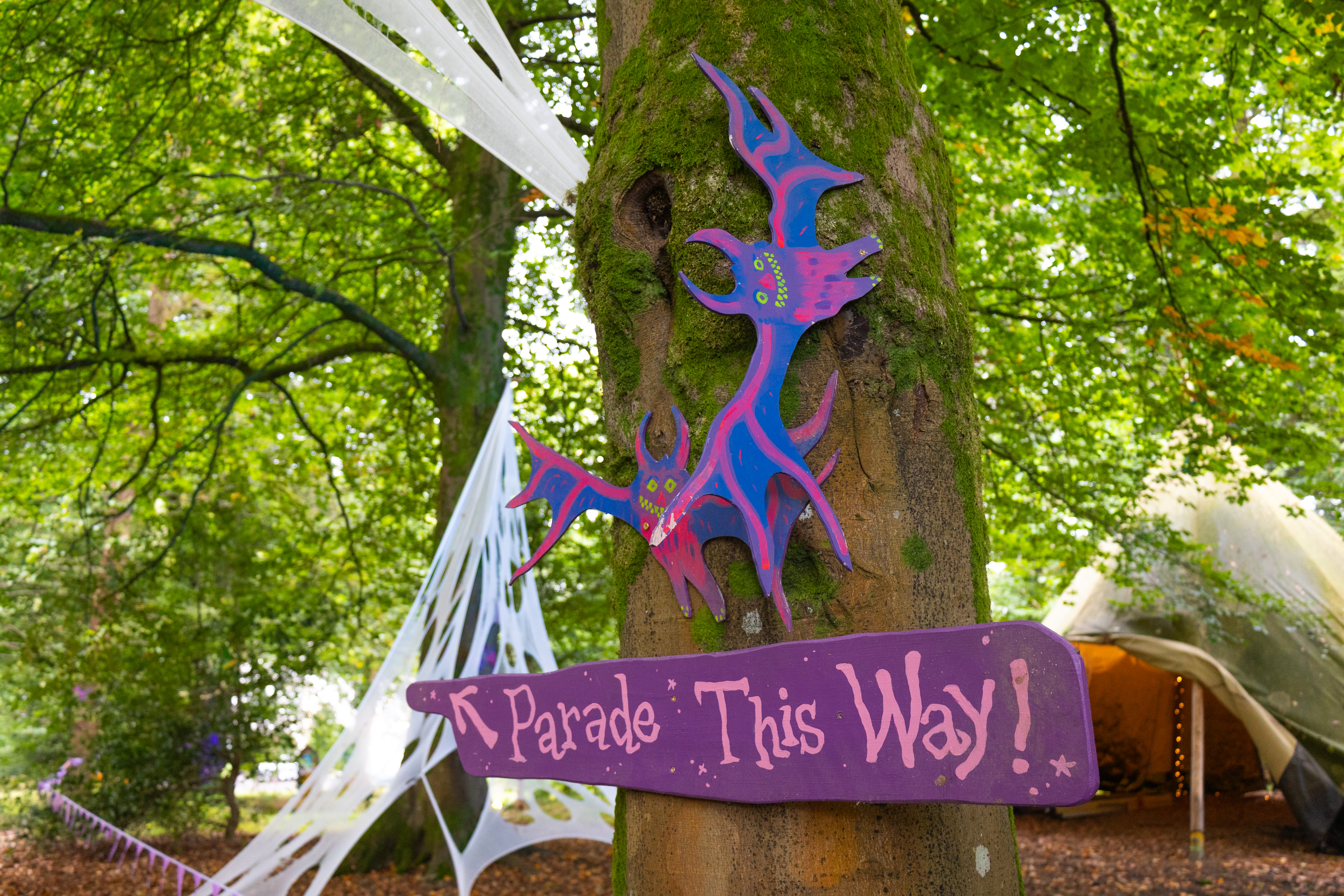 A sign pointing towards a Halloween trail with two bats hanging above.