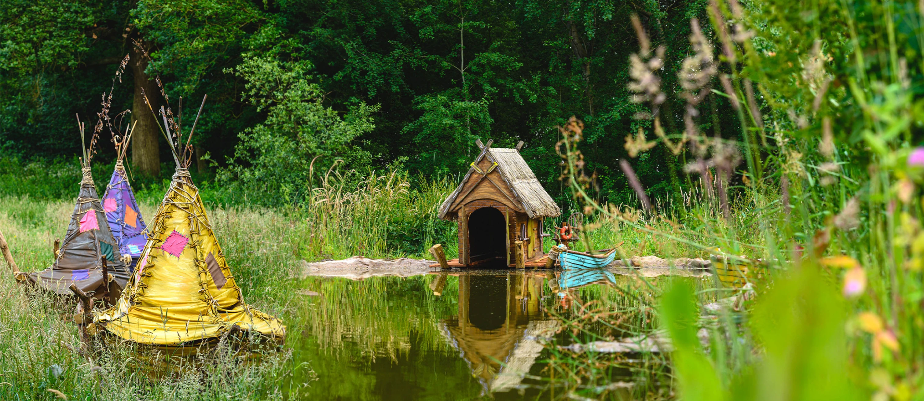 Boggle boat house and colourful houses by the lake at Bewilderwood